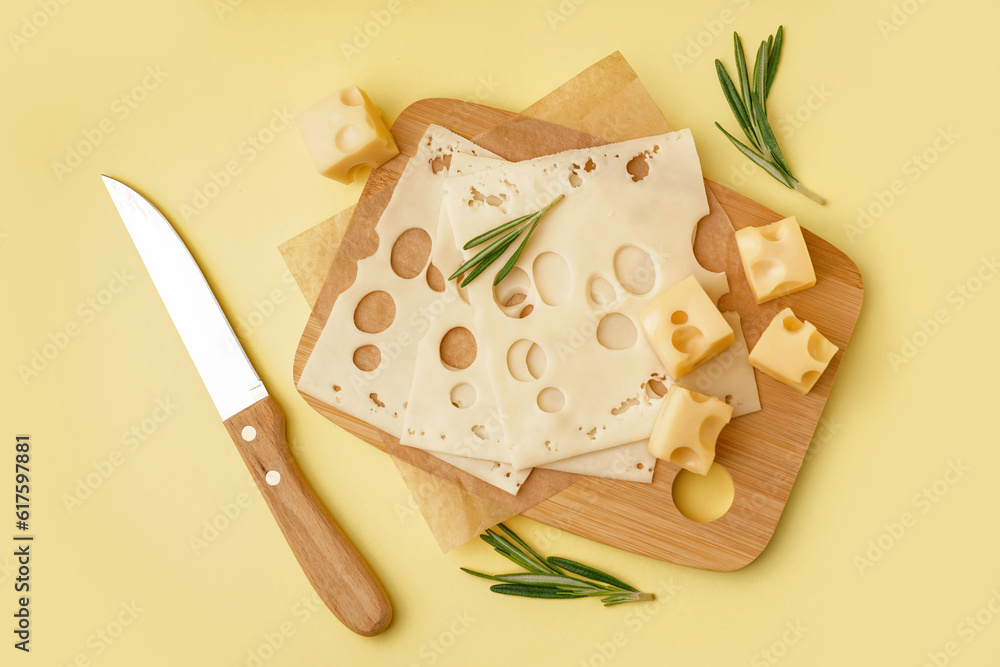 Board with pieces of Swiss cheese on yellow background