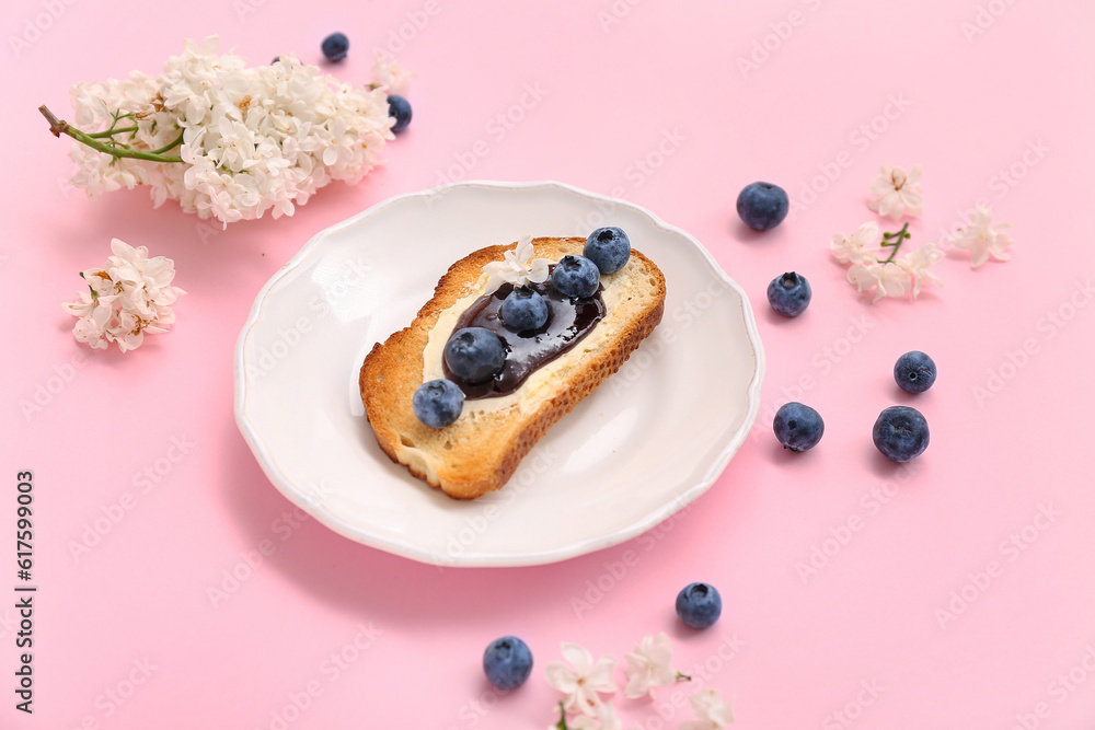 Plate with delicious jam toast, blueberries and flowers on pink background