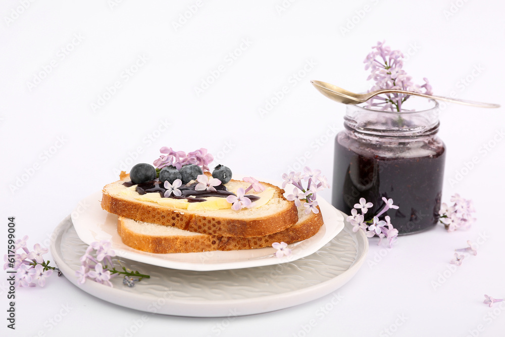 Plates with delicious jam toasts, blueberries and flowers isolated on white background