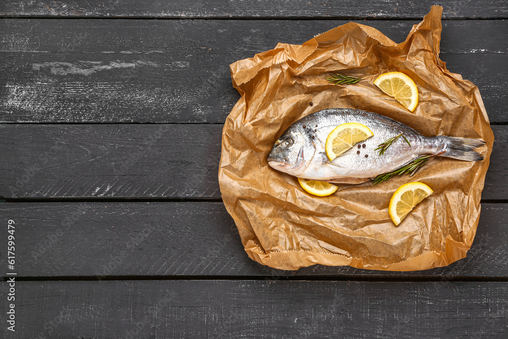 Raw dorado fish with lemon on dark wooden background