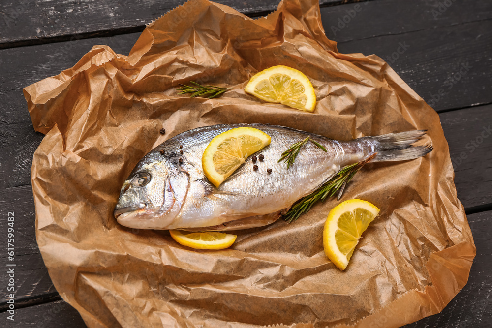 Raw dorado fish with lemon on dark wooden background