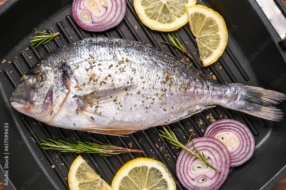 Raw dorado fish with lemon and onion on grill pan