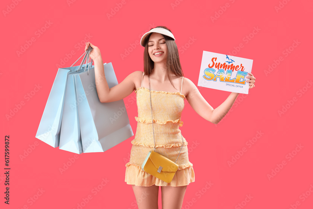 Young woman holding paper with text SUMMER SALE and shopping bags on red background