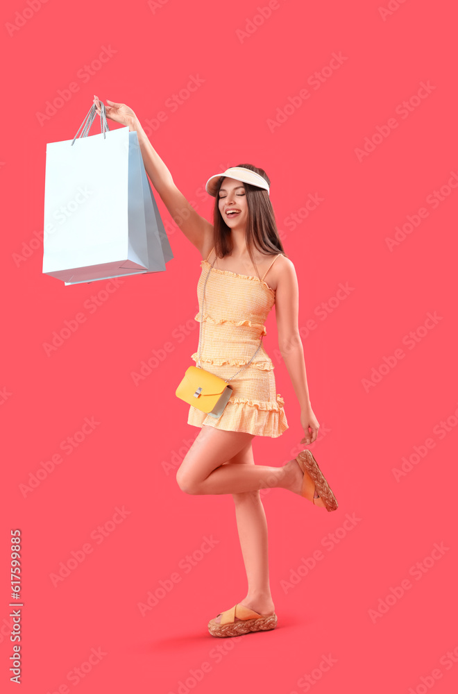 Young woman with shopping bags on red background