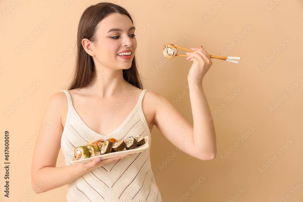 Young woman with sushi on beige background