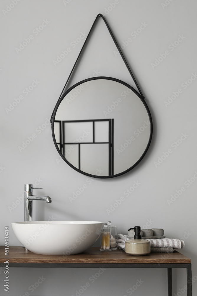 Table with sink bowl, bath accessories and mirror in bathroom