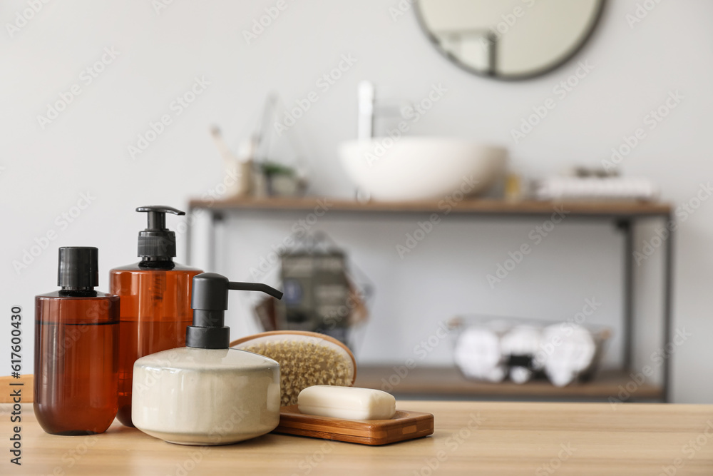 Soap dispenser, bar and bath accessories on wooden table in bathroom, closeup