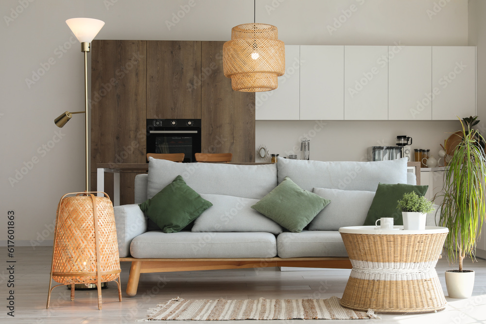 Interior of light living room with cozy grey sofa, coffee table and glowing lamps