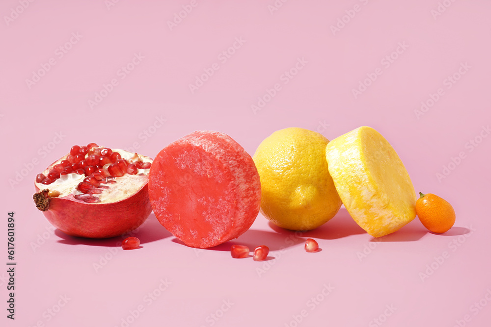 Solid colorful shampoo bars with lemon, kumquat and pomegranate on pink background