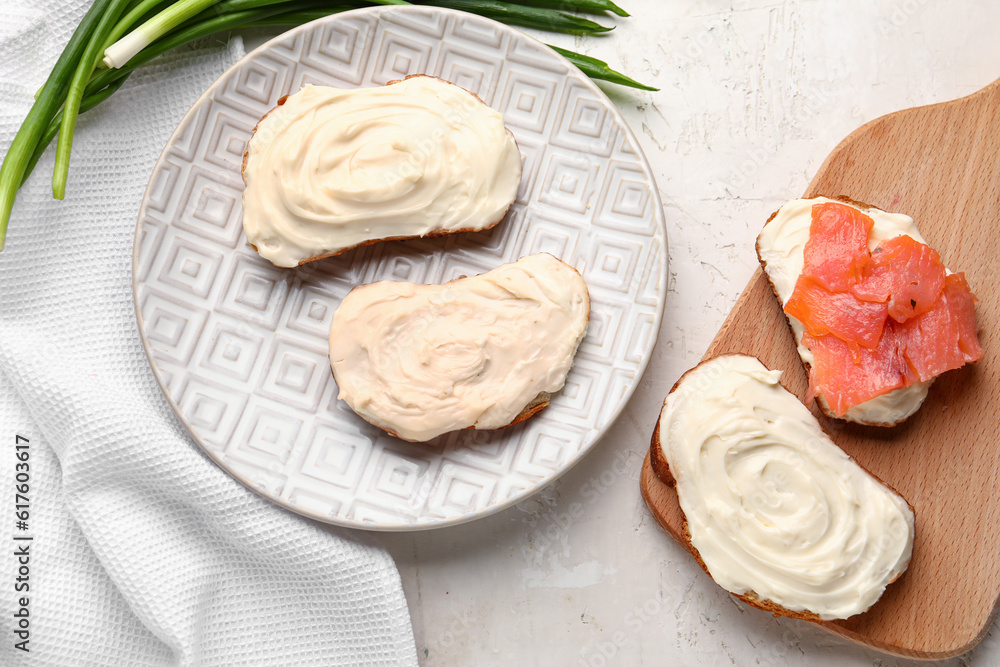 Plate of tasty sandwiches with cream cheese and fish on light background