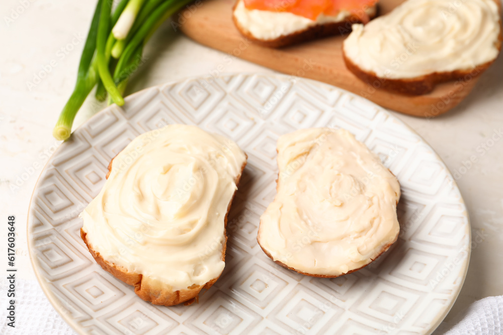 Plate of tasty sandwiches with cream cheese on light background