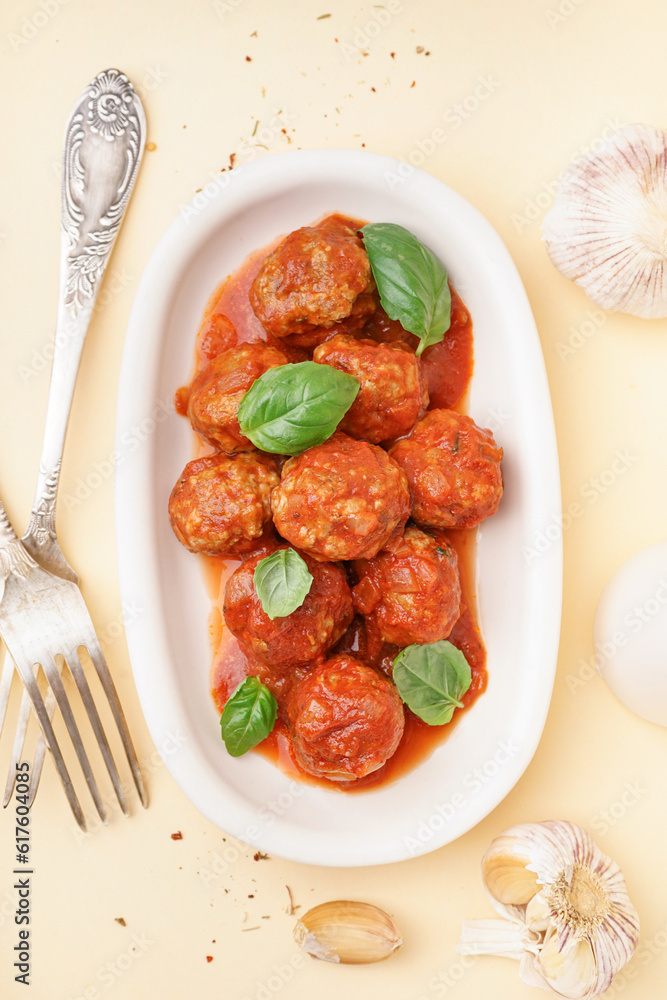 Plate of tasty meat balls with tomato sauce and basil on beige background