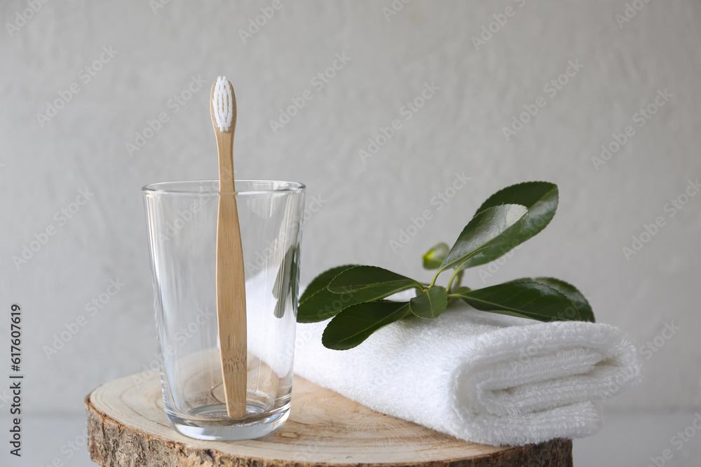 Bamboo tooth brush in glass and towel on grey background