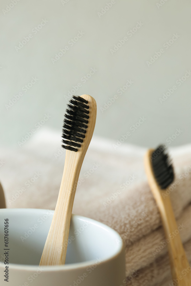 Bamboo tooth brushes and towels on grey background, closeup