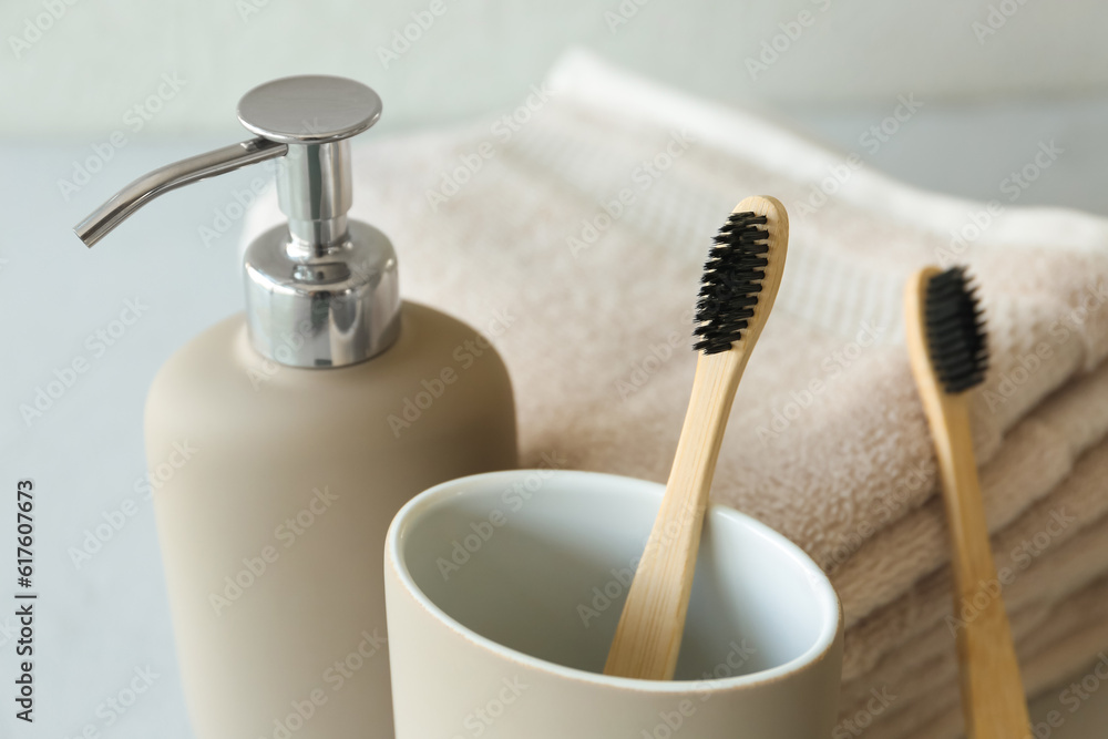 Bamboo tooth brushes, liquid soap and towels on grey background, closeup