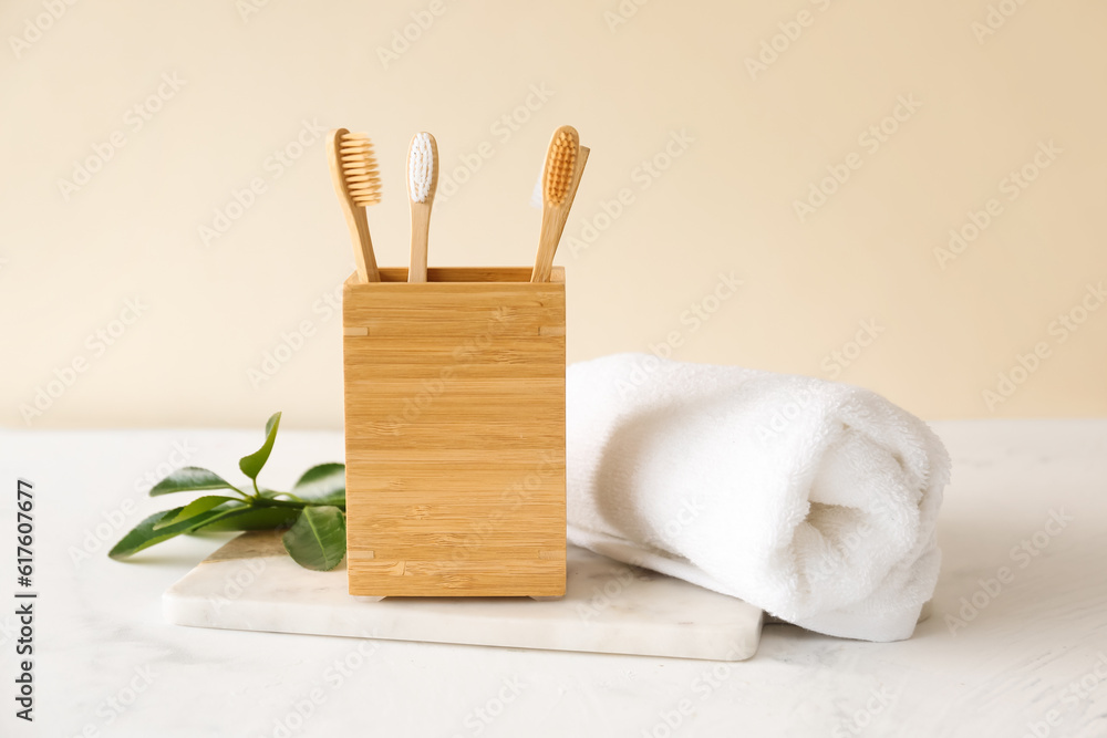 Bamboo tooth brushes in holder and towel on light background