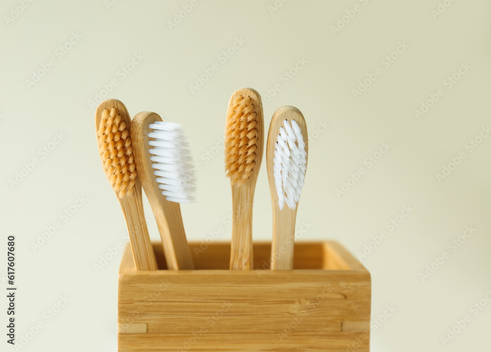 Bamboo tooth brushes in holder on light background, closeup