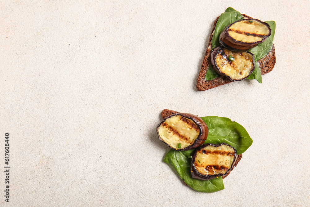 Toasts with delicious grilled eggplants on light background, top view