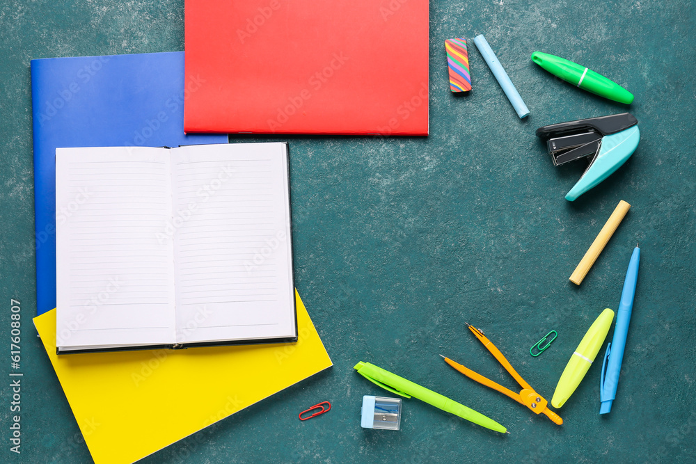 Notebooks with different school stationery on turquoise background