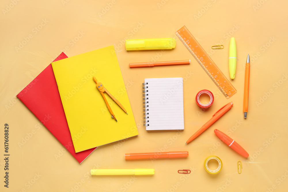 Notebooks with different school stationery on orange background