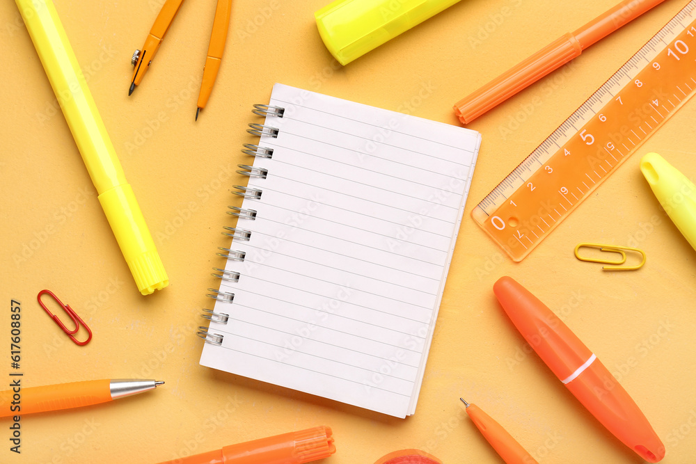 Notebook with different school stationery on orange background