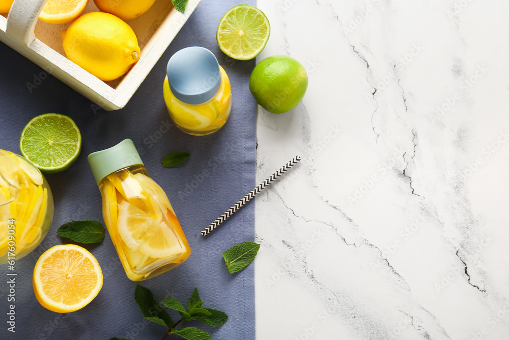 Bottles of infused water with lemon on white marble background