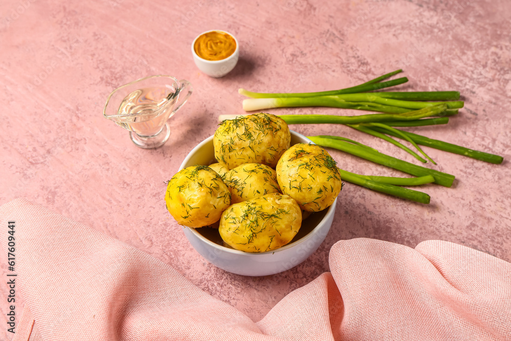 Bowl of boiled baby potatoes with dill and green onion on pink background