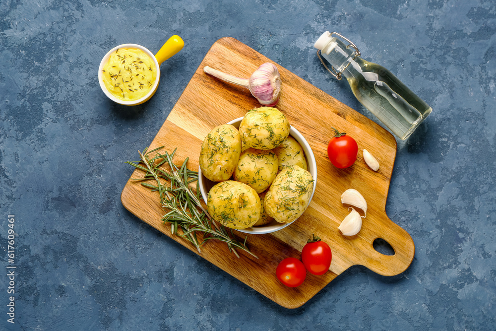 Bowl of boiled baby potatoes with dill and tomatoes on blue background