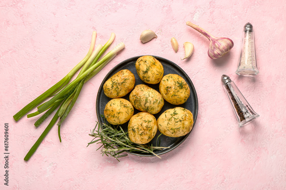 Plate of boiled baby potatoes with dill and green onion on pink background