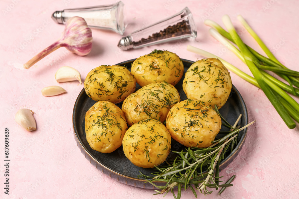 Plate of boiled baby potatoes with dill and green onion on pink background