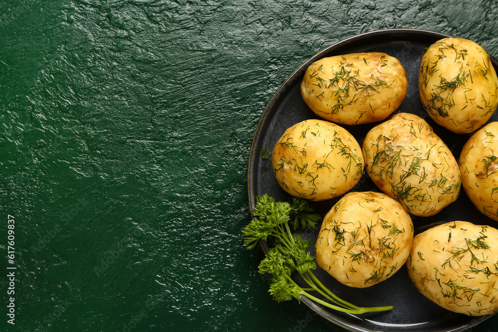 Plate of boiled baby potatoes with dill and parsley on green background