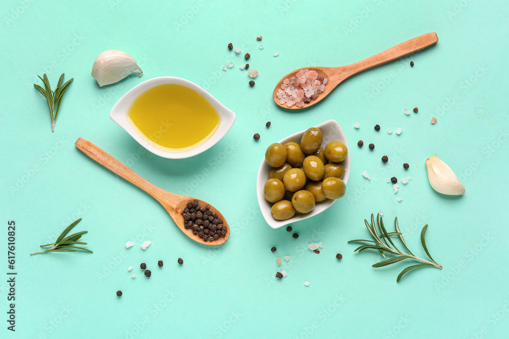 Bowls with ripe olives and oil on turquoise background