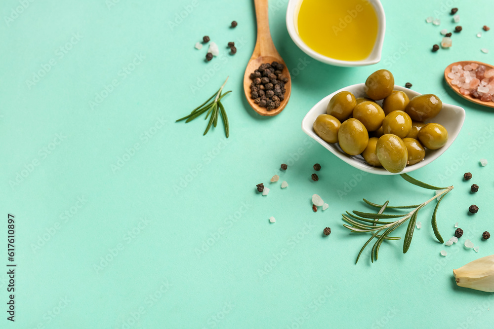 Bowls with ripe olives and oil on turquoise background