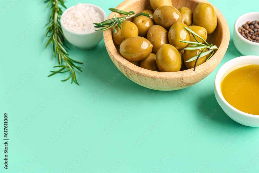 Bowls with ripe olives and oil on turquoise background