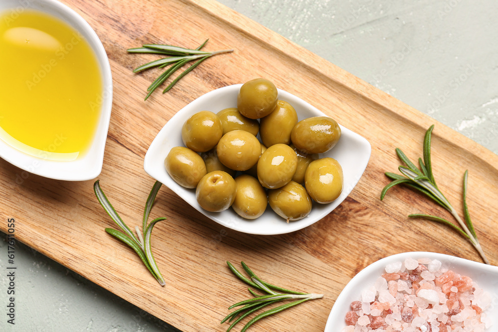 Bowls with ripe olives, salt and oil on light background