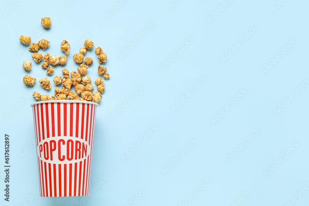 Bucket with tasty popcorn on blue background