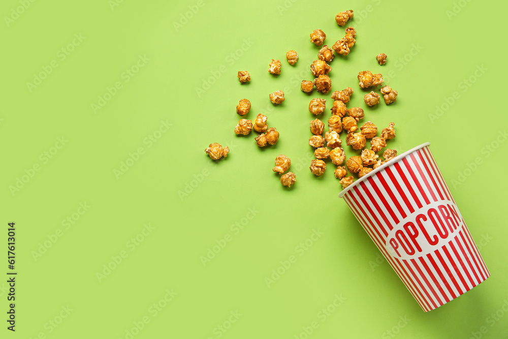 Bucket with tasty popcorn on green background