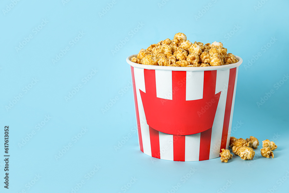 Bucket with tasty popcorn on blue background