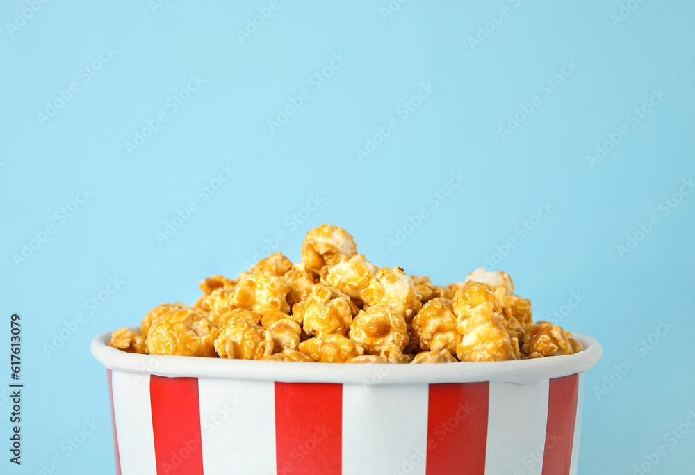 Bucket with tasty popcorn on blue background