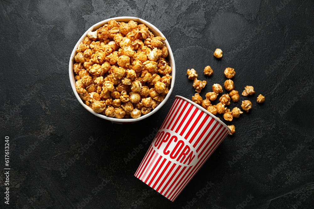 Buckets with tasty popcorn on black background