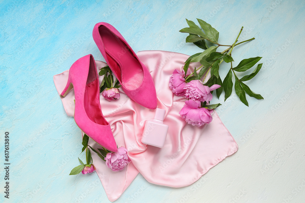 Composition with bottle of perfume, silk scarf, high heels and beautiful peony flowers on light blue