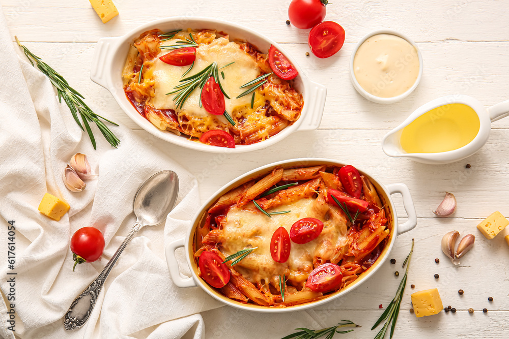 Baking dishes of pasta with tomato sauce and cheese on white tile background