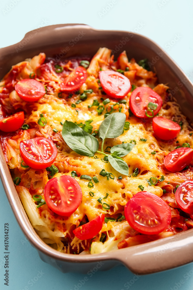 Baking dish of pasta with tomato sauce and cheese on blue background