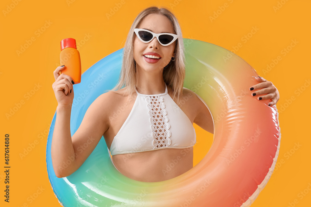 Young woman with sunscreen cream on yellow background