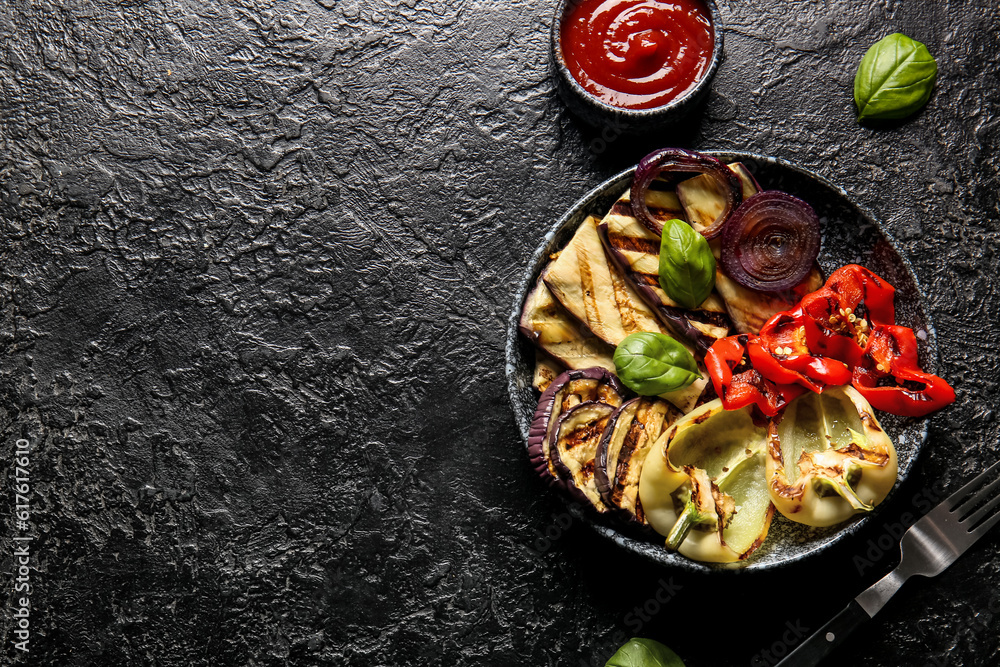 Plate with tasty grilled vegetables and sauce on black background