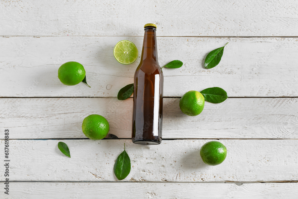 Bottle of cold beer with lime on light wooden background