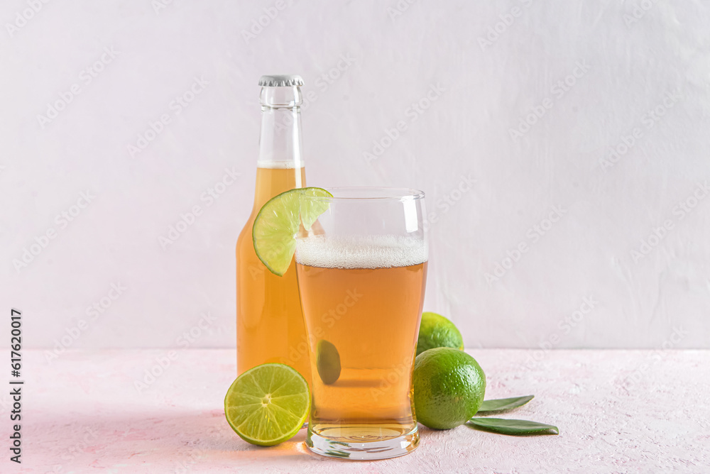 Glass and bottle of cold beer with lime on light background