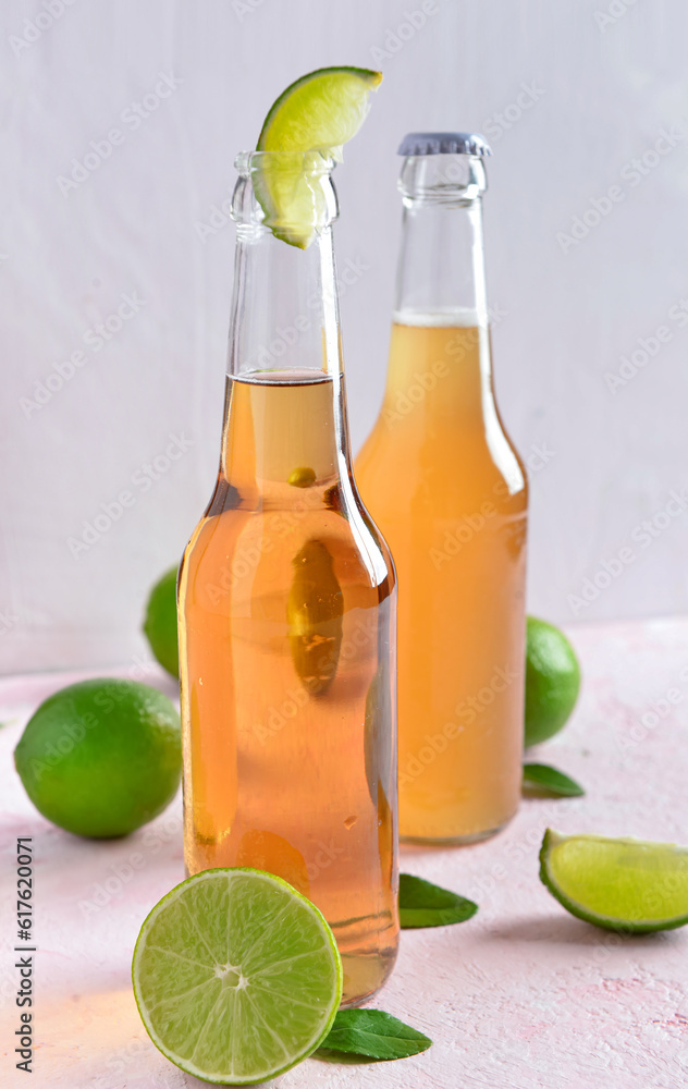 Bottles of cold beer with lime on light background