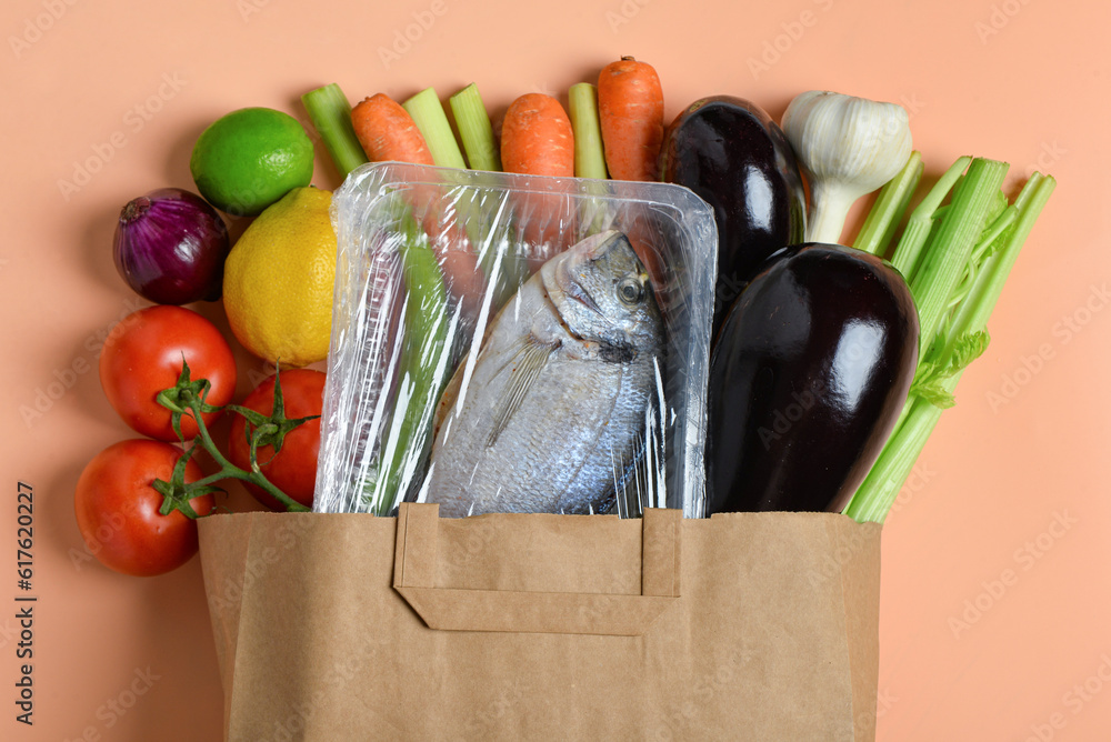 Paper bag with different products on orange background