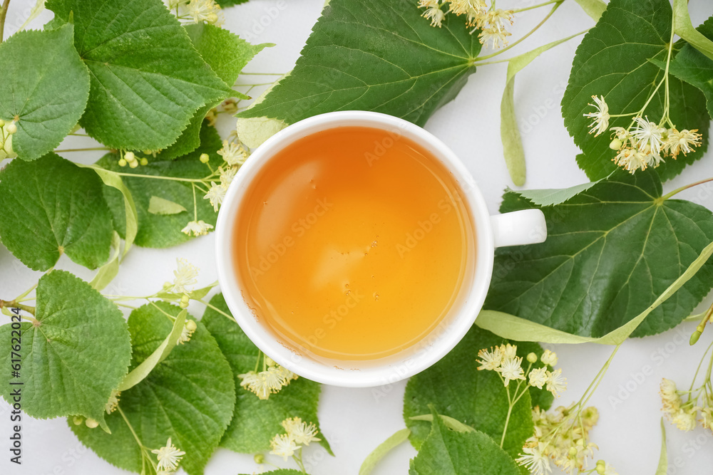 Cup of linden tea and leaves on white background